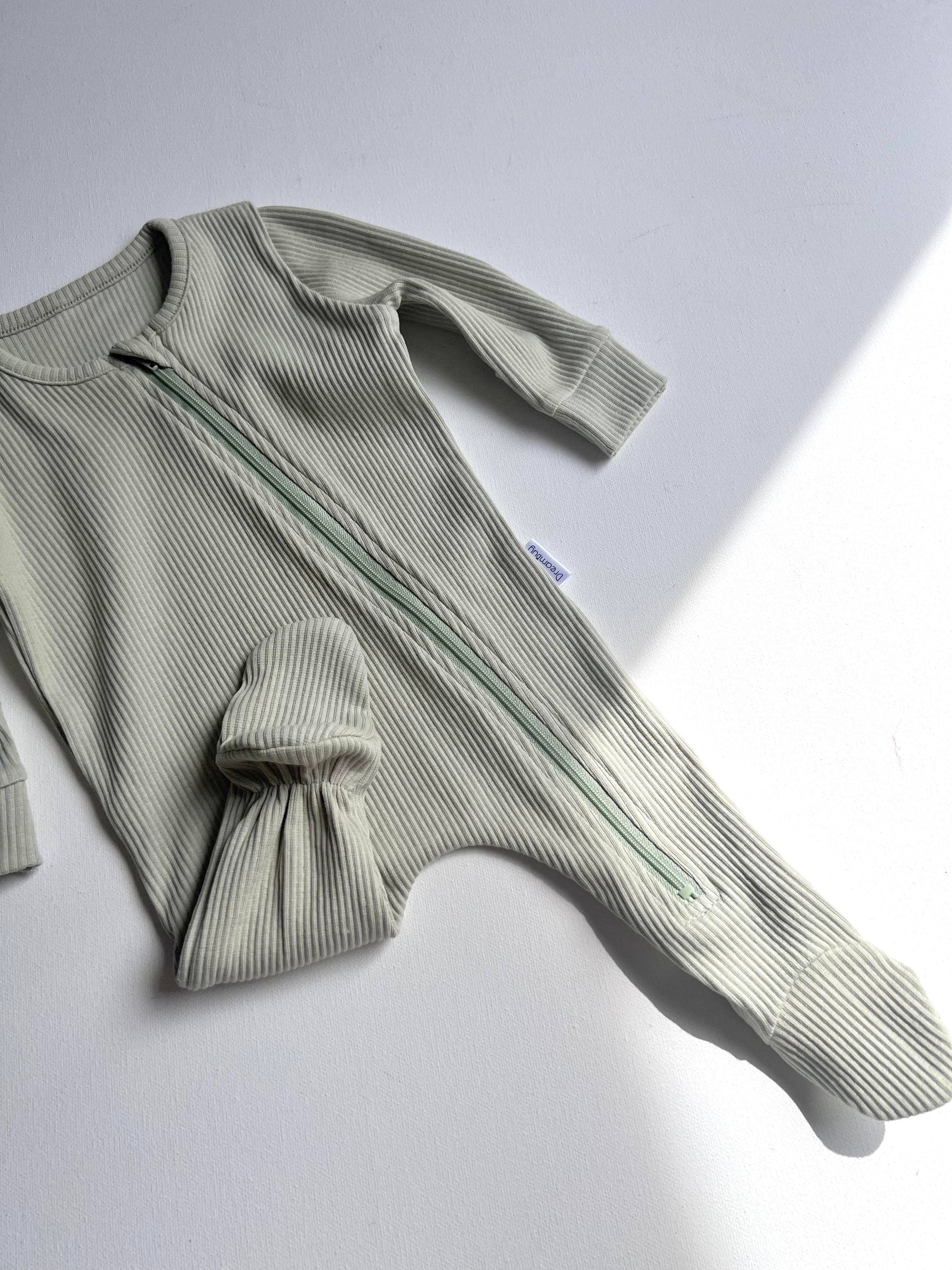 Green ribbed baby romper on a light gray background