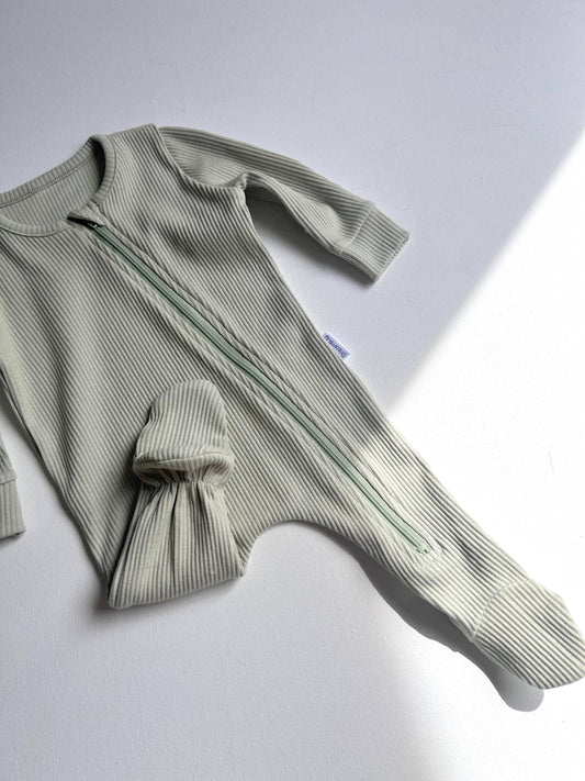 Green ribbed baby romper on a light gray background