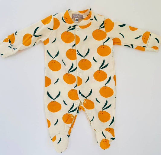 Baby wearing a sleepsuit with orange pattern on a white background