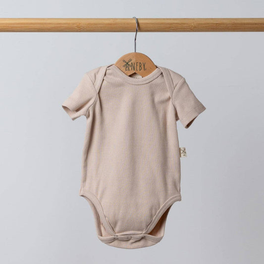 Three baby bodysuits in beige, pink, and blue hanging on a rack with 'Nenby' branding.