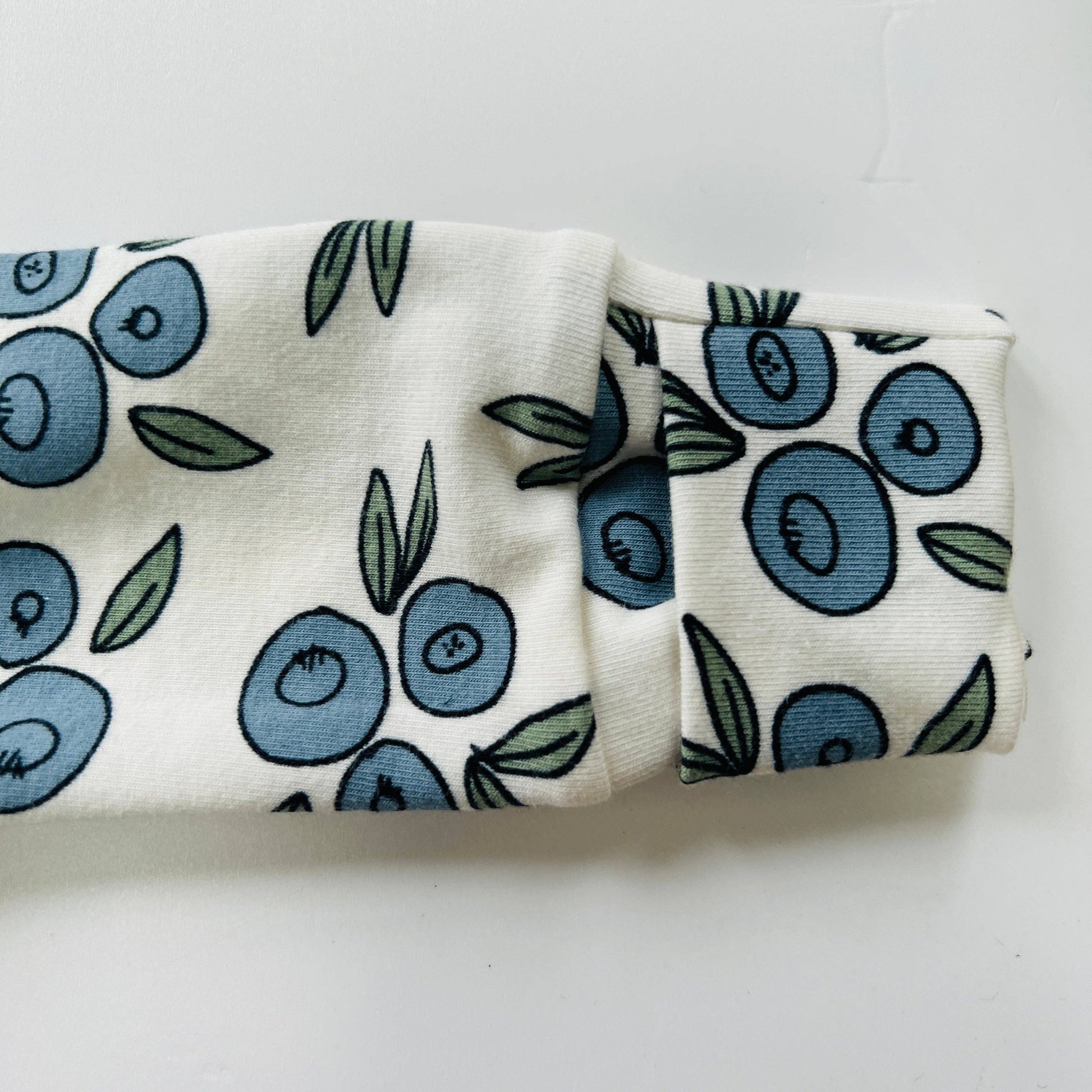 Baby sleepsuit with blueberry pattern on a white background