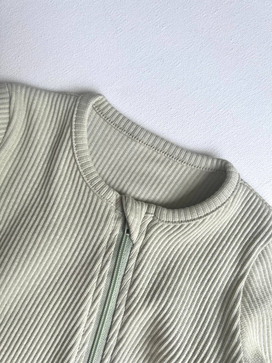 Green ribbed baby romper on a light gray background