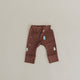 Brown baby pants with tree patterns on a beige background