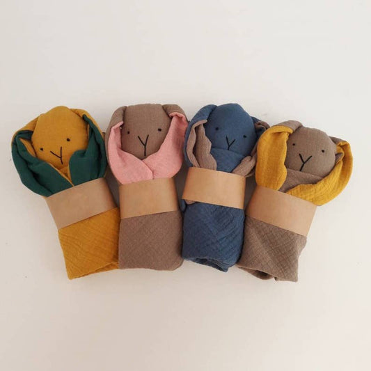 Four plush toys wrapped in colorful cloths on a white background