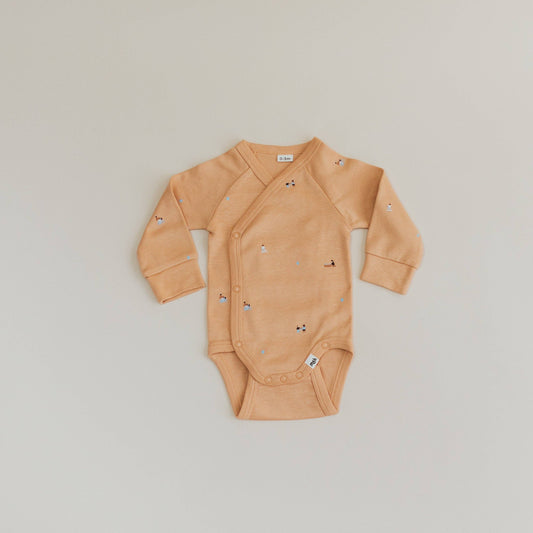 Beige baby onesie with small patterns on a light gray background