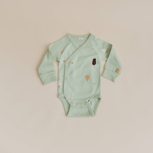 Mint green baby onesie with tree designs on a beige background