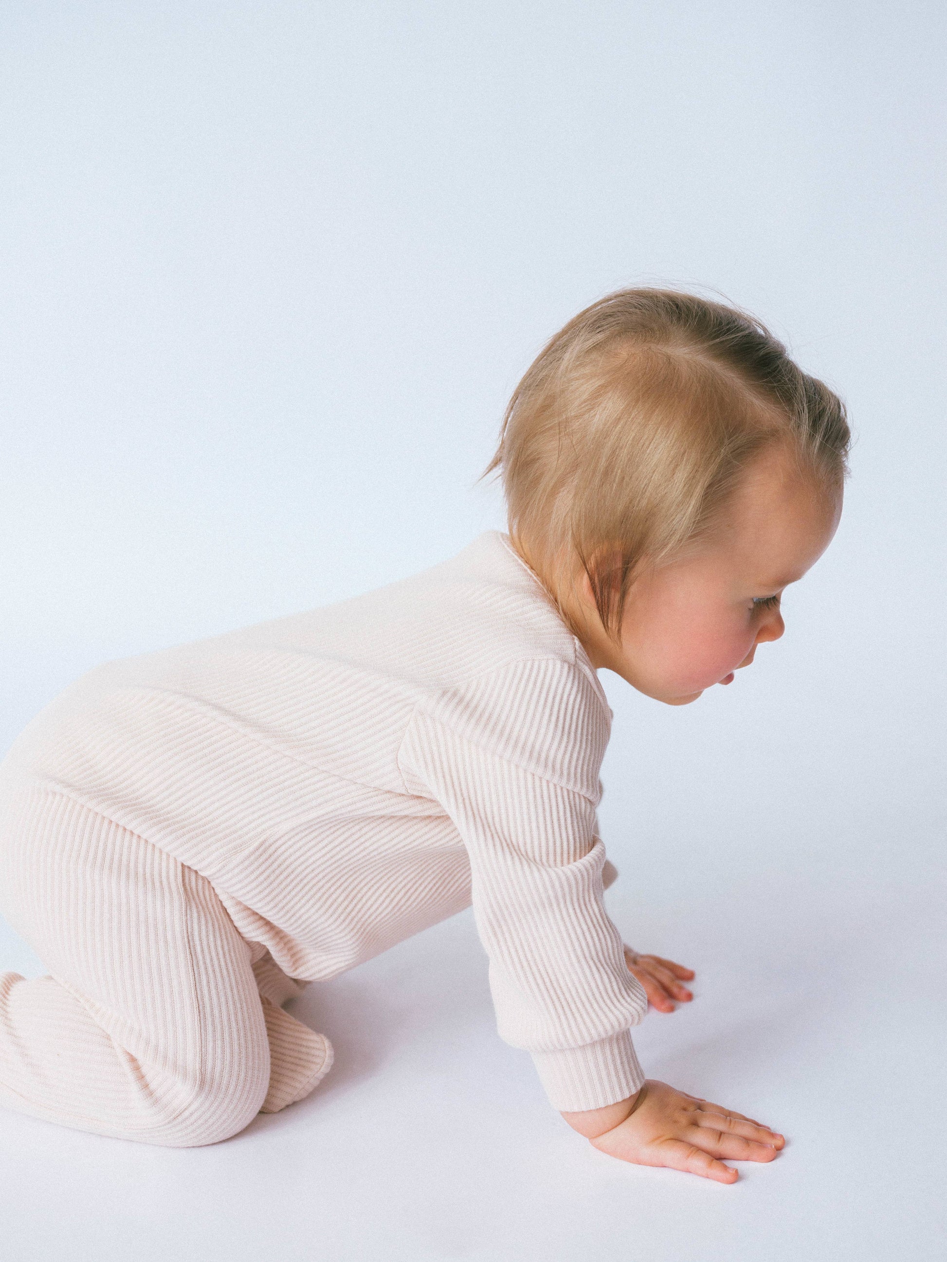 Baby in a light pink outfit on a white background
