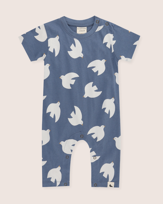 Baby wearing a blue outfit with white bird patterns on a light background