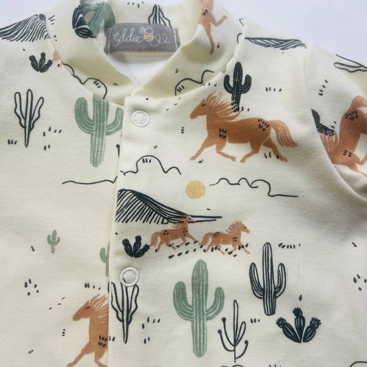 Baby sleepsuit with desert animal pattern on a light gray background