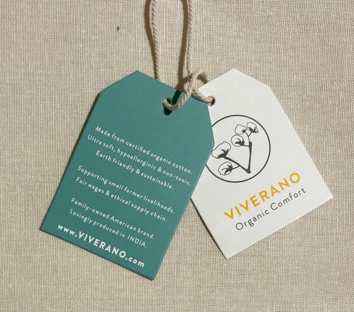 Two product tags on a beige fabric background, one green and one white, with 'Viverano' branding.