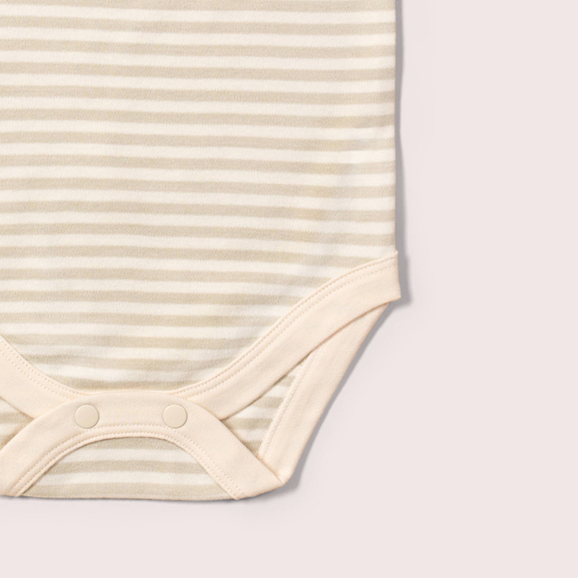 Close-up of a beige baby bodysuit with stripes on a light gray background
