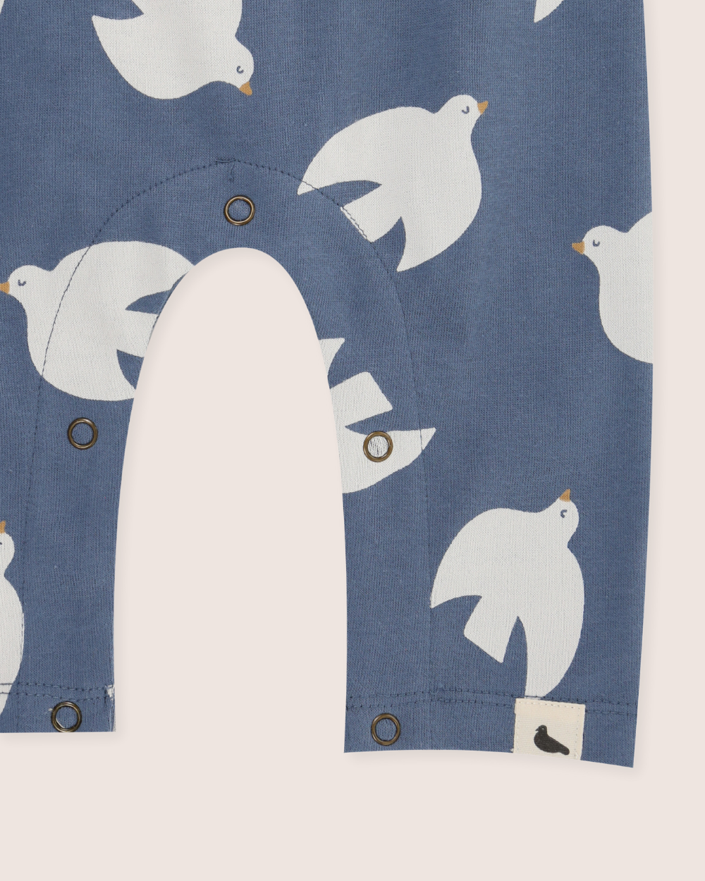 Close-up of a blue baby romper with white bird patterns and buttons.