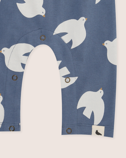 Close-up of a blue baby romper with white bird patterns and buttons.