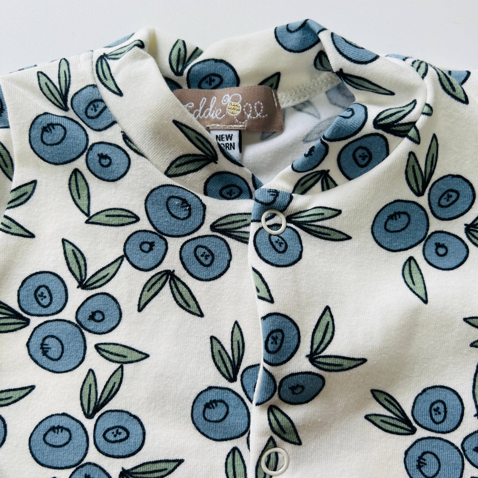 Baby sleepsuit with blueberry pattern and  label on a white background