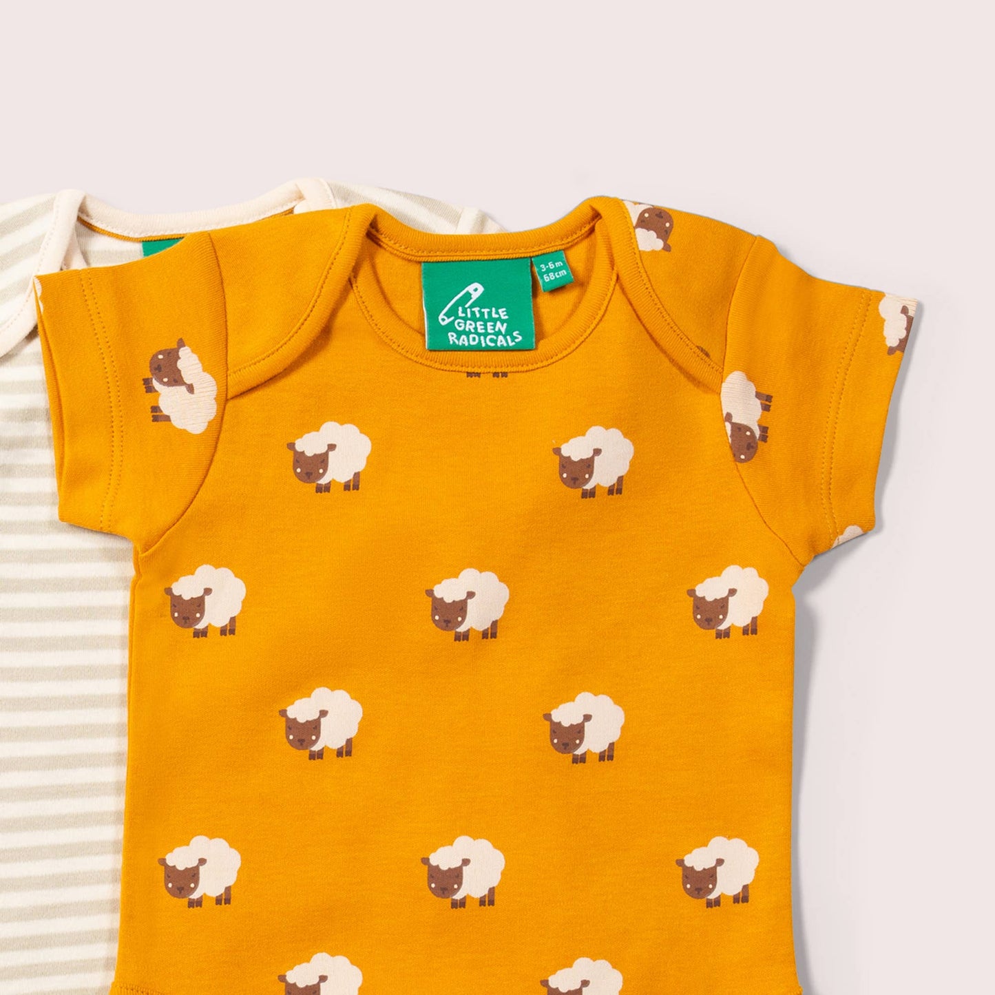 Yellow bodysuit with sheep pattern and 'Little Green Radicals' brand on a white background