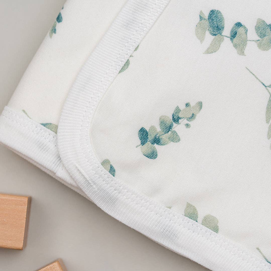 White fabric with green leaf pattern on a neutral background