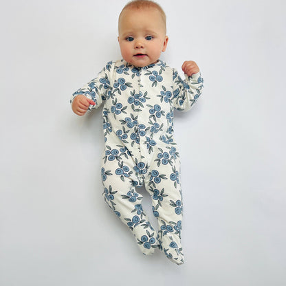 Baby wearing a floral sleepsuit on a plain background