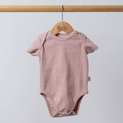 Pink baby bodysuit on a wooden hanger against a light gray background