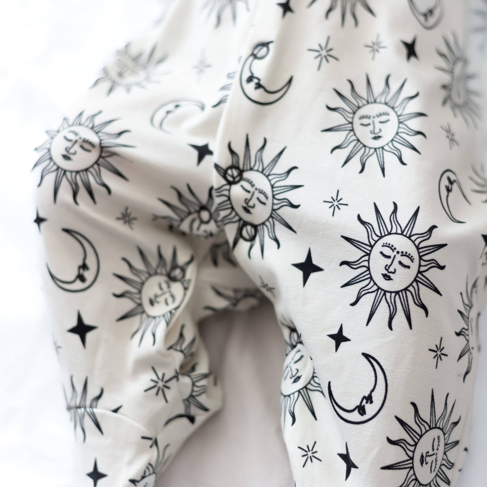 White sleepsuit with black sun and moon patterns
