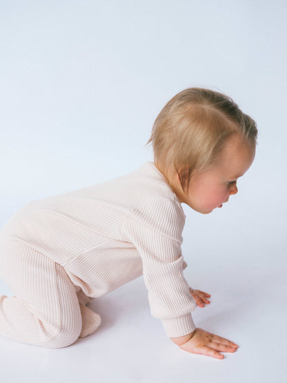 Baby in a light pink outfit on a white background