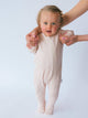 Child wearing a beige ribbed romper with a plain background