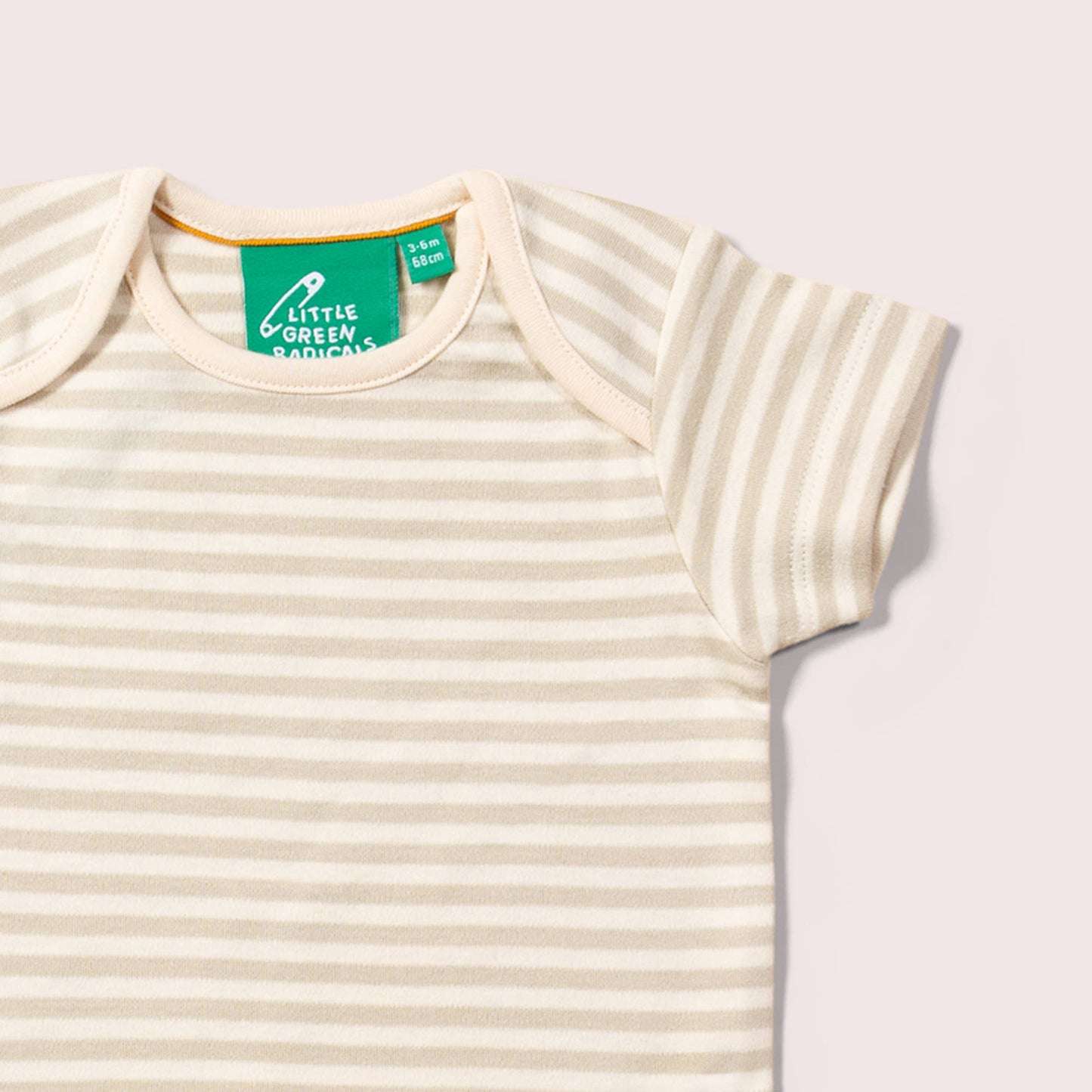 Beige striped baby bodysuit with a green tag on a light background