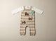 Striped baby dungaree with toy truck pattern on a beige surface